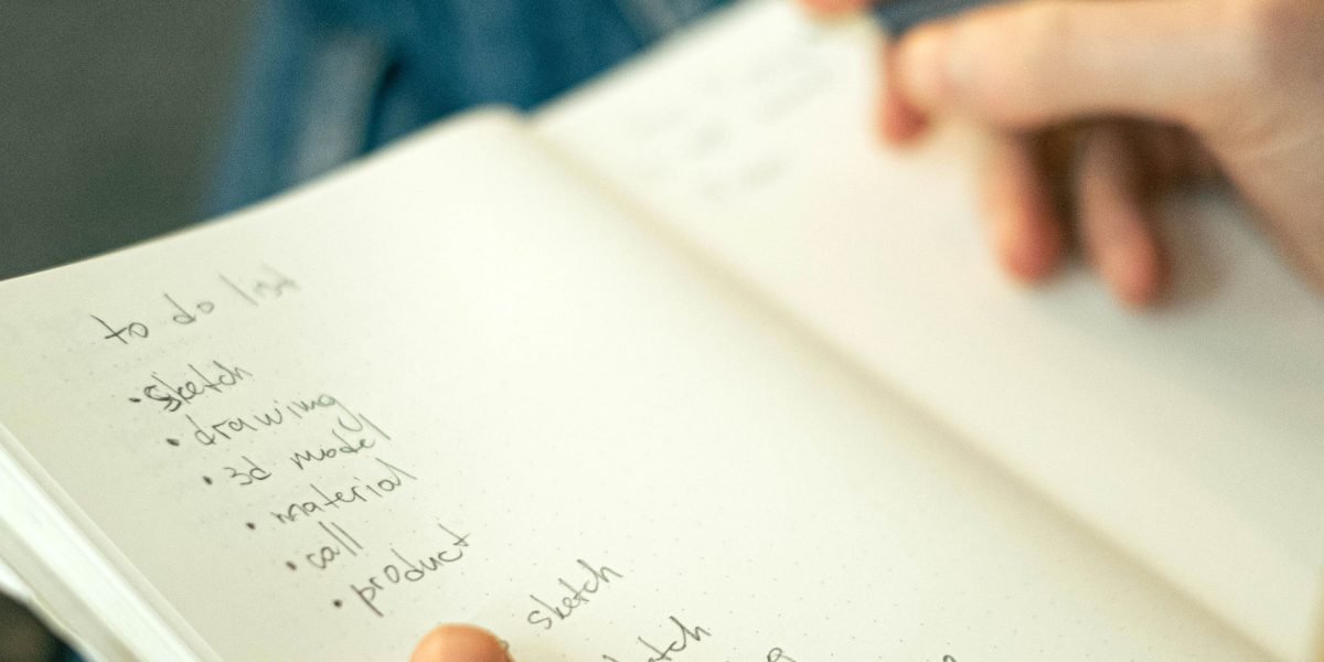 A person writing down or organizing a reading list in a notebook, demonstrating a structured approach.